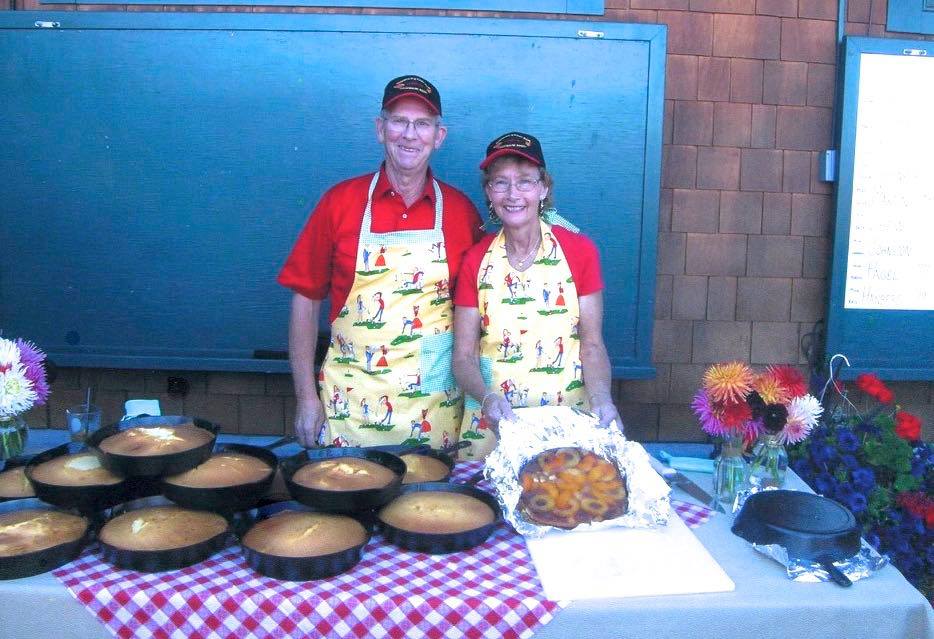Larry and Marg O'Neil surrounded by 9 pineapple peach upside down cakes made in vintage Griswold cast iron skillets.