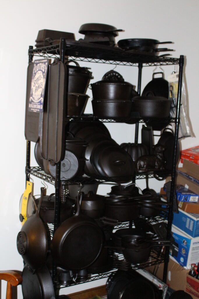 John Clough display of vintage a cast iron in his guest bedroom including a wok, griddles, skillets and Dutch ovens, and a Loth poster. 