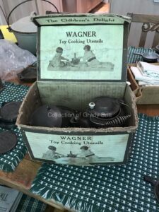 Box with vintage Wagner Ware cast iron toy cooking utensils from the collection of Grady Britt. 