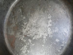 Vintage cast iron pan with flaking and fire damage