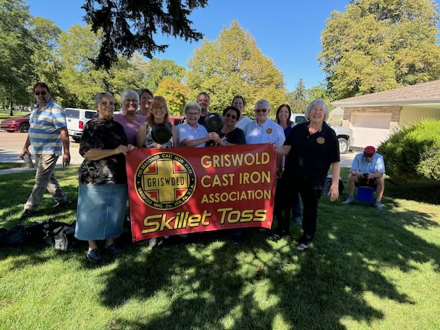 Ladies holding a "Griswold Cast Iron Association Skillet Toss" sign. 