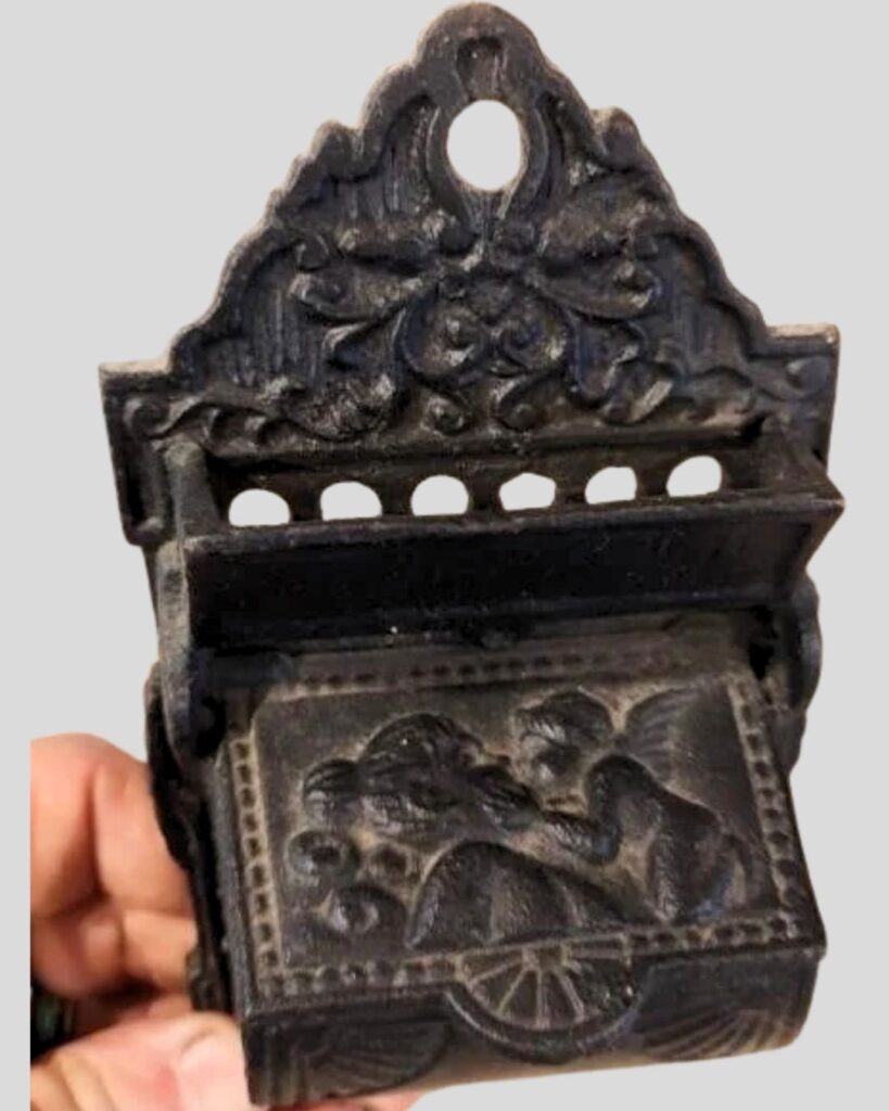 Vintage cast iron match keeper with embossed girl and cherup or angel on lid.