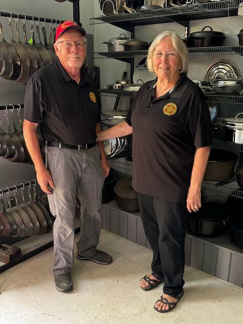 Doug and Kathy Wenz pictured in Doug's workshop in front of part of their vintage and antique cast iron collection. 
