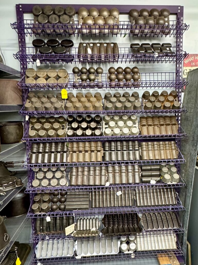 Vintage and antique cast iron gem and muffin pans on shelves in Doug Wenz's workshop. 