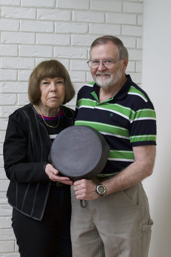 Roy Meadows and Jane Brymer holding a cast iron skillet. 