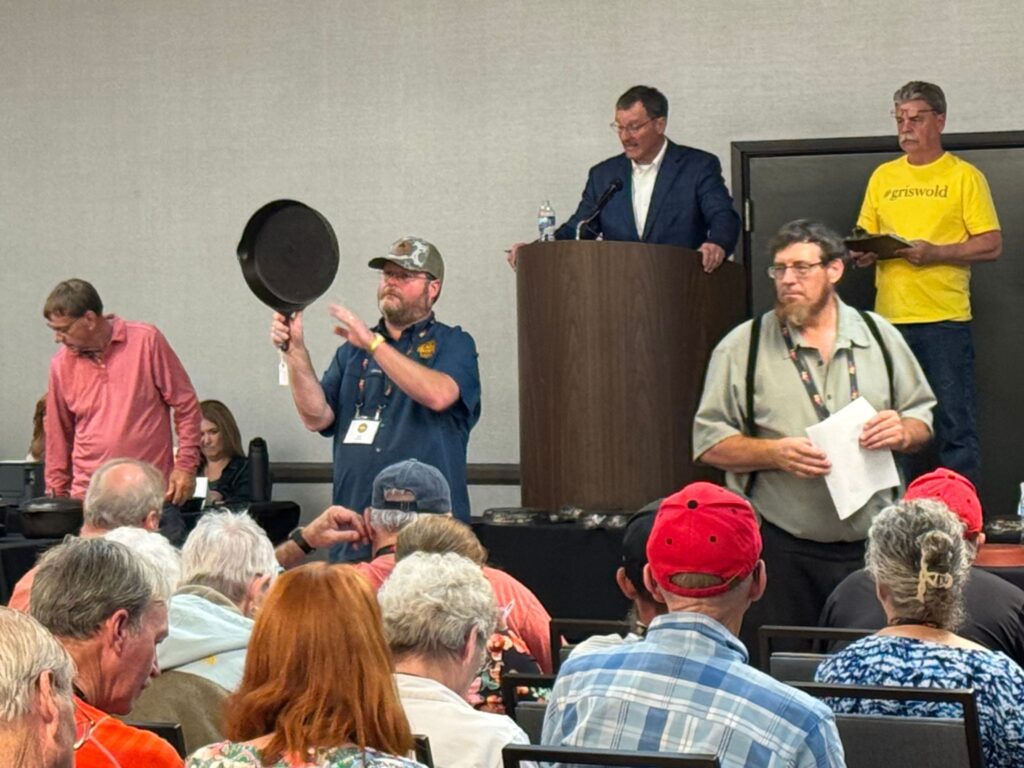 Cast iron auction at the cast iron convention, with ring man holding a vintage Griswold no. 13 milled bottom cast iron skillet. 