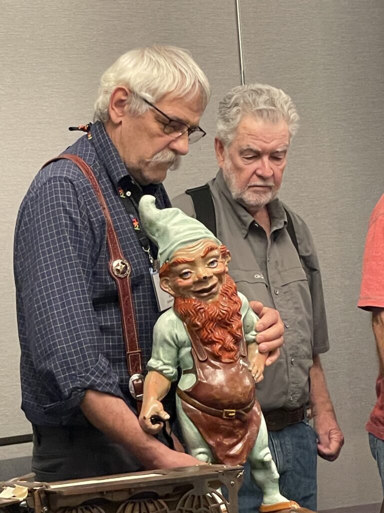 Brad Schwarting and Russ howser showing and discussing a large antique cast iron gnome at the cast iron convention. 